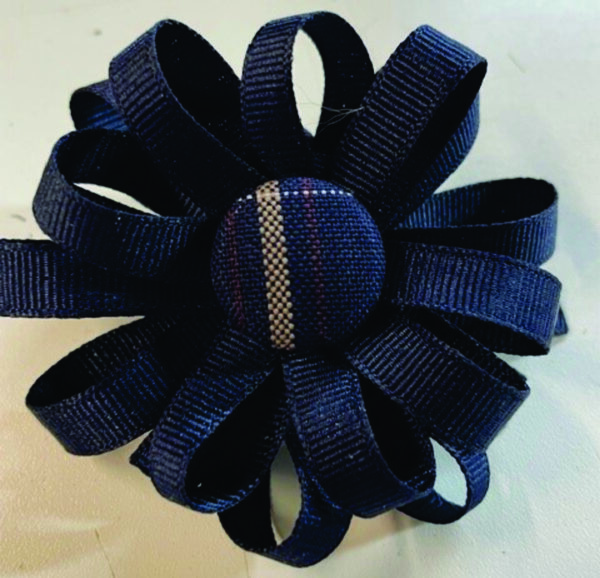 Navy ribbon flower with central button.