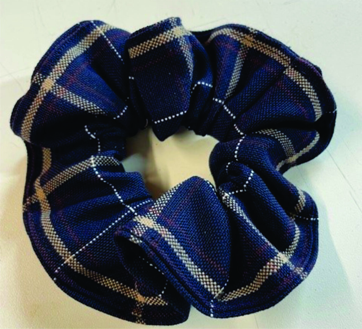 Navy plaid fabric scrunchie on white background.